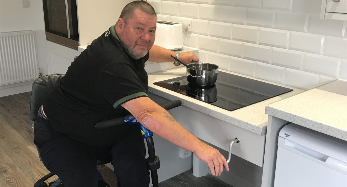 Tony Downs, paralympic sailor, using adjustable hob cooker at Island Riding Centre